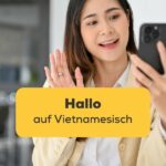 Vietnamesische Frau winkt in die Handykamera um Hallo auf Vietnamesisch zu sagen