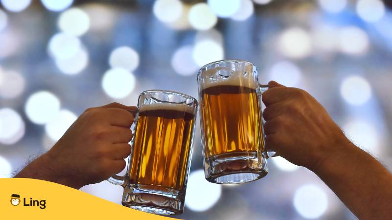 Zwei Hände mit vollen Biergläsern stoßen an
